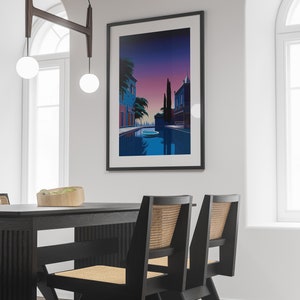 May include: A framed print of a colorful illustration depicting a canal scene with buildings, trees, and a boat. The scene is set at dusk with a purple and pink sky.
