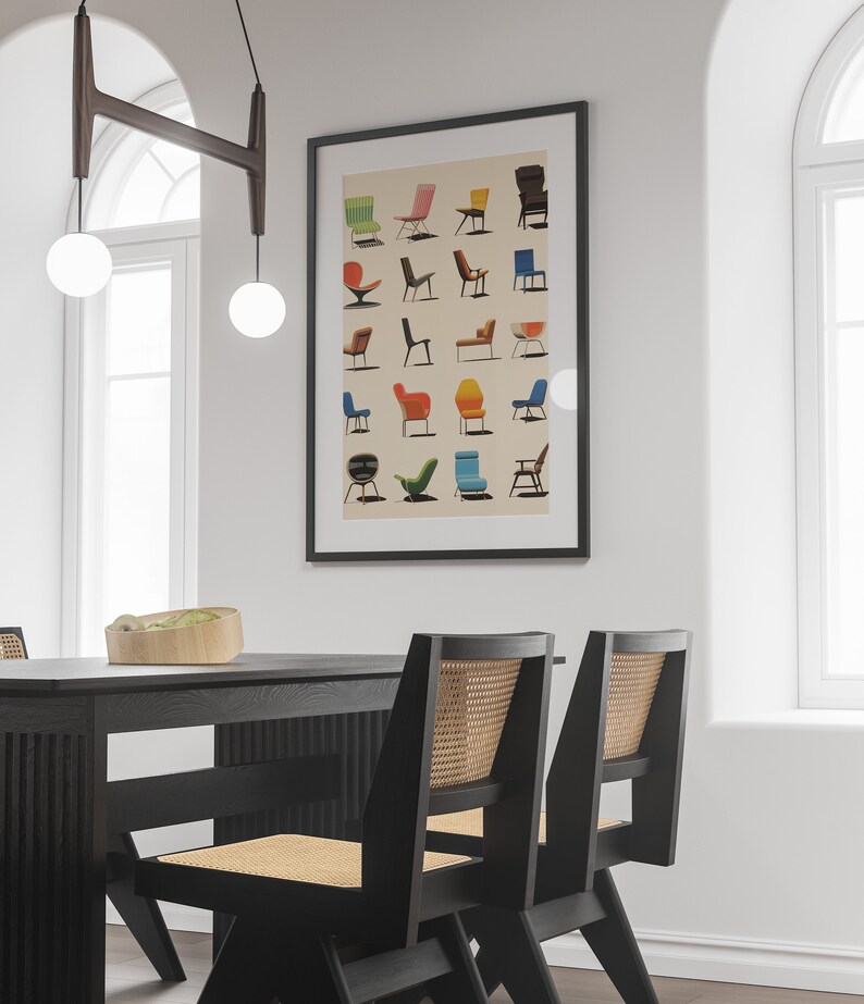 K&ouml;nnte beinhalten: Ein schwarzer gerahmter Poster mit wei&szlig;em Hintergrund, der eine Sammlung bunter St&uuml;hle zeigt. Der Poster h&auml;ngt an einer wei&szlig;en Wand &uuml;ber einem schwarzen Esstisch mit zwei schwarzen St&uuml;hlen mit geflochtenen Korbsitzen.