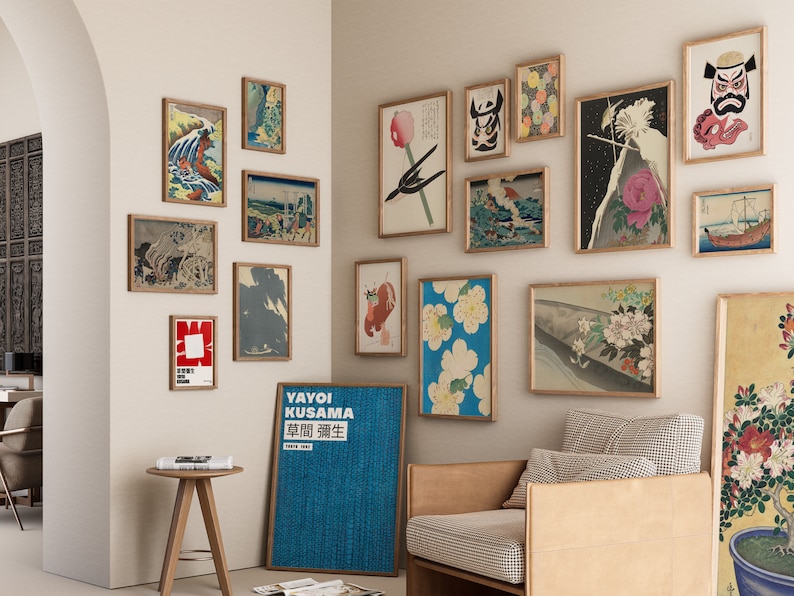 May include: A wall gallery featuring a variety of framed prints, including Japanese woodblock prints, abstract art, and a poster with Japanese text. The prints are arranged in a grid pattern and are hung on a white wall. A brown leather armchair and a small wooden table are in the foreground.