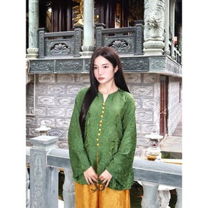 May include: A long-sleeved green tunic featuring a subtle tonal floral pattern, a small V-neckline, and a vertical row of small yellow buttons down the center front, paired with loose-fitting yellow trousers with a matching tonal floral pattern.