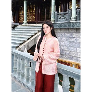 May include: A light pink long-sleeved shirt with a subtle floral pattern and a vertical row of dark red buttons down the front, paired with loose-fitting dark red trousers. The shirt features a mandarin collar and long, straight sleeves.