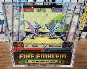 May include: A clear acrylic display case with a 3D pop-up scene from the video game Fire Emblem: The Sacred Stones. The scene features two characters, Valter and Cormag, battling each other with their weapons. The display case also includes the characters' stats and weapon information.
