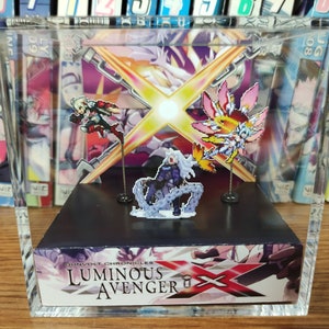 May include: A clear acrylic display case with a black base and a colorful anime character figurine inside. The case has a printed image on the bottom with the text "GUNVOLT CHRONICLES LUMINOUS AVENGER X".