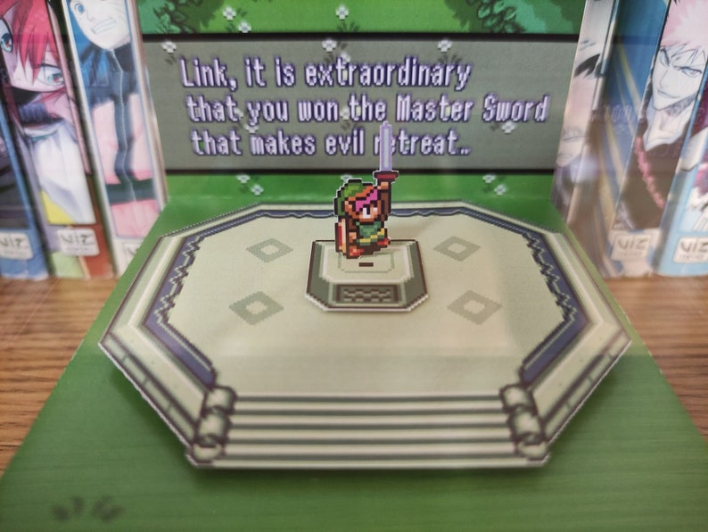 May include: A green, pixelated, 3D pop-up of Link from the Legend of Zelda video game series. Link is holding a sword and standing on a platform with a green background. The text "Link, it is extraordinary that you won the Master Sword that makes evil retreat..." is visible in the background.