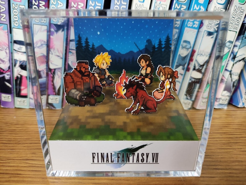 May include: A pixel art diorama of Final Fantasy VII characters around a campfire under a starry sky, encased in a clear acrylic block. The game's logo is visible on the front. The scene evokes a sense of nostalgia.