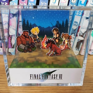 May include: A pixel art diorama of Final Fantasy VII characters around a campfire under a starry night. The scene is enclosed in a clear acrylic block, with the game's logo at the base. The diorama is a collectible item.