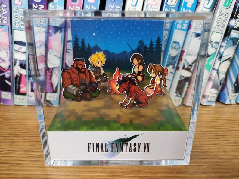 May include: A pixel art diorama of Final Fantasy VII characters around a campfire under a starry night. The scene is enclosed in a clear acrylic block, with the game's logo at the base. The diorama is a collectible item.