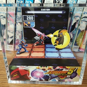 May include: A clear acrylic display case containing a 3D papercraft model of a video game scene. The scene features characters from Mega Man 5, including Mega Man, Proto Man, and a robot master. The display case has a black background with a diamond pattern and the text "CUSTOM" and "280" at the top. The bottom of the display case features the Mega Man 5 logo.