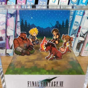 May include: A pixel art diorama of Final Fantasy VII characters around a campfire under a starry sky, within a clear acrylic box. The game's logo is displayed at the base of the diorama.