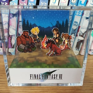 May include: A clear acrylic display featuring a pixelated scene from Final Fantasy VII. The scene depicts characters gathered around a campfire under a starry night sky. The Final Fantasy VII logo is displayed on the front.