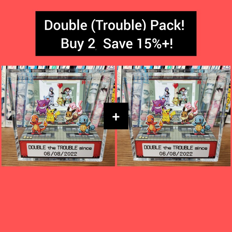 Puede incluir: Dos cajas de exhibici&oacute;n de acr&iacute;lico transparente con tem&aacute;tica de Pok&eacute;mon. Cada caja contiene una colecci&oacute;n de figuras de Pok&eacute;mon, incluyendo Pikachu, Charmander, Bulbasaur, Squirtle y un personaje de Pok&eacute;mon rojo y negro. Las cajas tienen una etiqueta roja y blanca que dice "DOUBLE the TROUBLE since 06/08/2022".