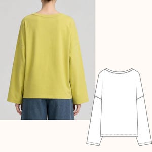 May include: A chartreuse long-sleeve shirt with a wide, rounded neckline and dropped shoulder seams. The garment features a loose, boxy fit with straight-cut sleeves and a straight hemline, accompanied by a black and white line drawing sketch.