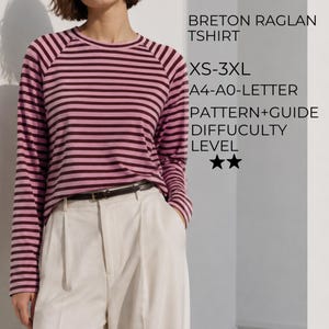 May include: A long-sleeve Breton raglan t-shirt with horizontal stripes in dark maroon and light pink. The text reads: BRETON RAGLAN TSHIRT, XS-3XL, A4-A0-LETTER, PATTERN+GUIDE, DIFFUCULTY LEVEL, and two stars. The shirt is paired with cream trousers.