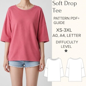 May include: A pink short-sleeved t-shirt with a round neckline and drop shoulders. The image includes text: Soft Drop Tee, PATTERN PDF+ GUIDE, XS-3XL, A0, A4, LETTER, DIFFICULTY LEVEL, and a star icon, plus two black and white line drawings of the shirt.