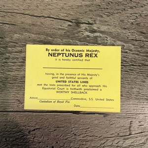 May include: A yellow certificate with the text "By order of his Oceanic Majesty, NEPTUNUS REX it is hereby certified that having, in the presence of His Majesty's good and faithful servants of UNITED STATES LINES met the tests prescribed for all who approach His Equatorial Court is forthwith proclaimed a WORTHY SHELLBACK Attest Commodore, S.S. United States Custodian of Royal Fin Date"