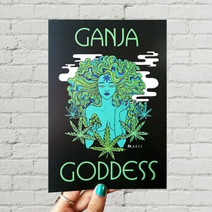 May include: A black and green print with the text "GANJA GODDESS" in green. The print features a woman with long green and blue hair holding a marijuana leaf.
