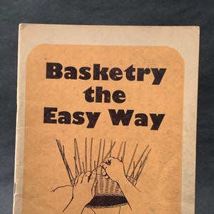 Puede incluir: Un libro titulado "Basketry the Easy Way" de O. R. Scott. La portada presenta una ilustración en blanco y negro de manos tejiendo una cesta.