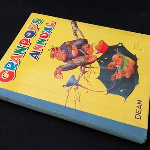 May include: A yellow book with the title "Granpop's Annual" in colourful letters. The cover features a cartoon illustration of monkeys on a tree branch with an umbrella.