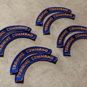 Puede incluir: Nueve parches bordados azules y dorados que dicen "Training Command" en un arco curvo.