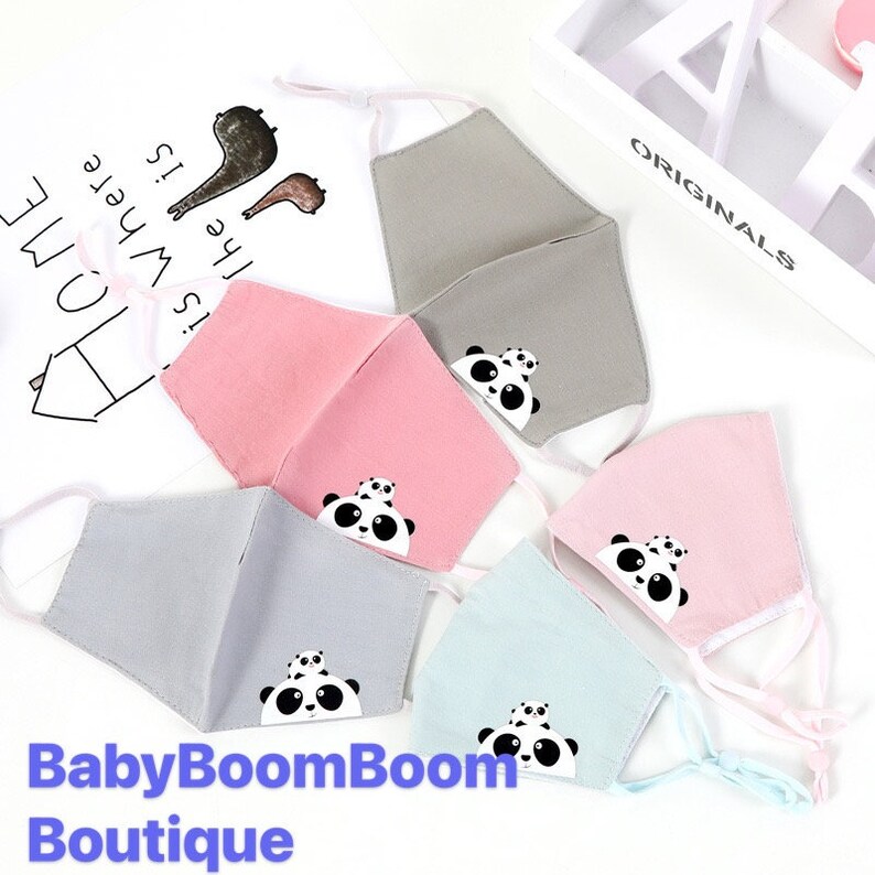 May include: Five fabric face masks with panda bear designs. The masks are in various colors, including pink, gray, and blue. The text "BabyBoomBoom Boutique" is at the bottom of the image.