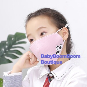 May include: A pink face mask with a panda bear design. The mask has adjustable ear loops and a white border. The text "BabyBoomBoom Boutique" is printed on the mask.