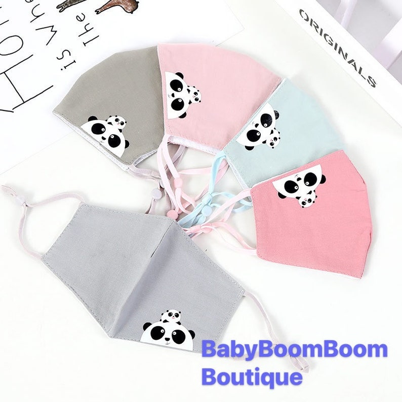 May include: Five fabric face masks with adjustable ear loops. Each mask features a different panda bear design in black and white. The masks are in shades of gray, pink, and light blue. The text "BabyBoomBoom Boutique" is printed on the bottom of the image.