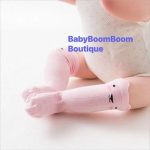 Könnte beinhalten: Ein Paar rosa Kniestrümpfe mit einem niedlichen Tiergesicht auf der Vorderseite. Die Socken sind gerippt und haben ein weiches, angenehmes Tragegefühl.