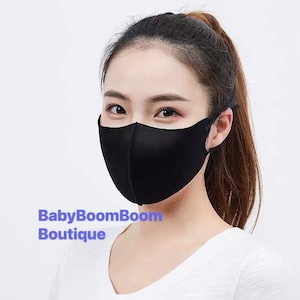 May include: A black face mask with a smooth, seamless design. The mask is worn by a person with long dark hair. The text "BabyBoomBoom Boutique" is visible in the lower left corner of the image.
