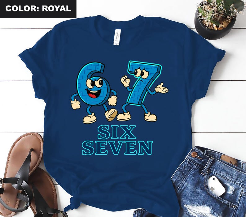 May include: Royal blue t-shirt featuring the numbers six and seven as cartoon characters with arms, legs, and facial expressions. The words "SIX SEVEN" are printed in a light blue, outlined font below the characters. The shirt is displayed on a white surface.