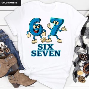 May include: White t-shirt featuring a cartoon design of the numbers six and seven in blue, with arms, legs, and facial expressions. The words "SIX SEVEN" are printed below the numbers in blue. The shirt is styled with jeans and boots.