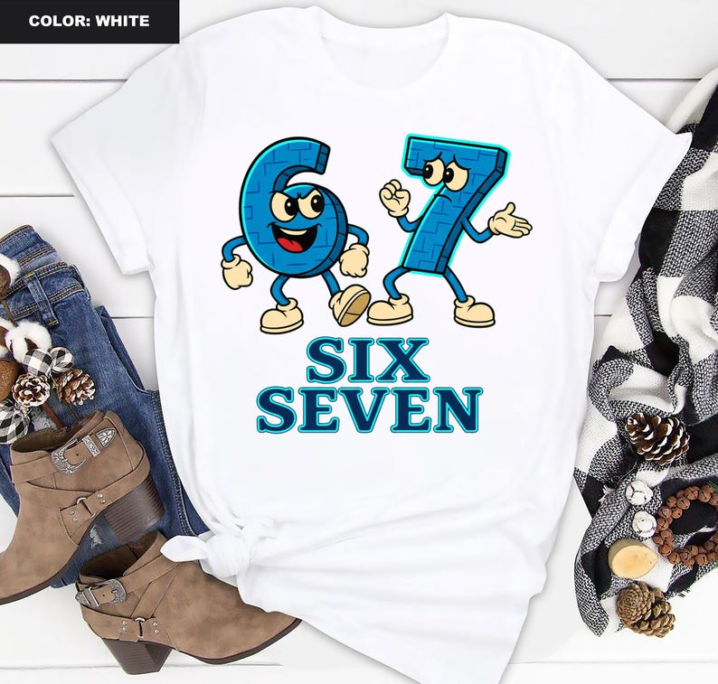May include: White t-shirt featuring a cartoon design of the numbers six and seven in blue, with arms, legs, and facial expressions. The words "SIX SEVEN" are printed below the numbers in blue. The shirt is styled with jeans and boots.