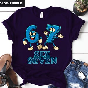 May include: Purple t-shirt featuring the numbers six and seven as cartoon characters with arms, legs, and facial expressions. The words "SIX SEVEN" are printed below the numbers in a blue, outlined font.