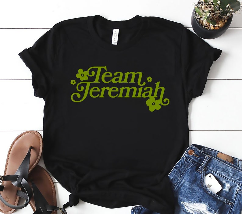 May include: Black t-shirt with the text "Team Jeremiah" in green with small flower graphics.