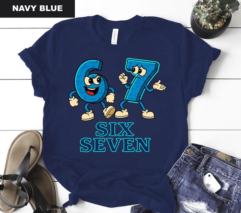 May include: Navy blue t-shirt featuring cartoon numbers six and seven with arms, legs, and facial expressions. The text "SIX SEVEN" is below the numbers in a blue, outlined font. The shirt is a casual, fun design.