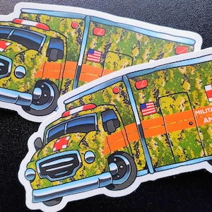Puede incluir: Dos pegatinas de dibujos animados de una ambulancia militar. La ambulancia es verde y amarilla con un patrón de camuflaje. La pegatina dice "Military Medicine Ambulance" en letras naranjas.