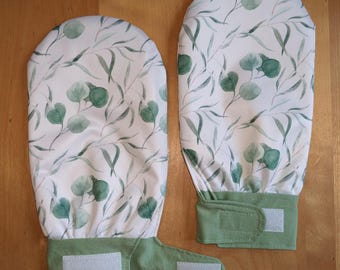 Könnte beinhalten: Zwei Stoffhandschuhe mit weißem Hintergrund und einem grünen Aquarell-Eukalyptusblatt-Muster. Jeder Handschuh hat ein einfarbiges salbeigrünes Bündchen mit einem Klettverschluss. Die Handschuhe sind oben abgerundet und haben eine flache Basis.