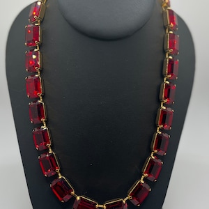 May include: A gold chain necklace with large, red, rectangular-shaped gemstones.