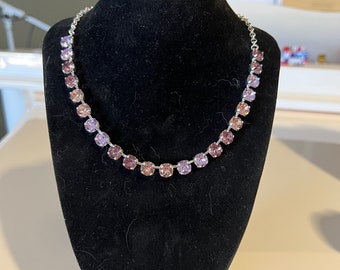 May include: A silver chain necklace with a gradient of light pink to dark purple round rhinestones.