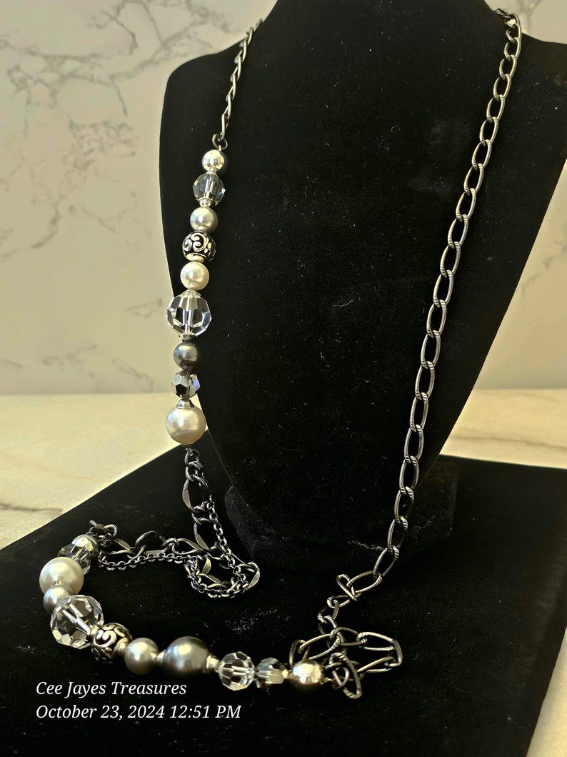 Puede incluir: Un collar largo de cadena plateada con una cadena plateada y cuentas de perlas blancas y cristal. El collar se muestra sobre un fondo de terciopelo negro. Cee Jayes Treasures 23 de octubre de 2024 12:51 PM