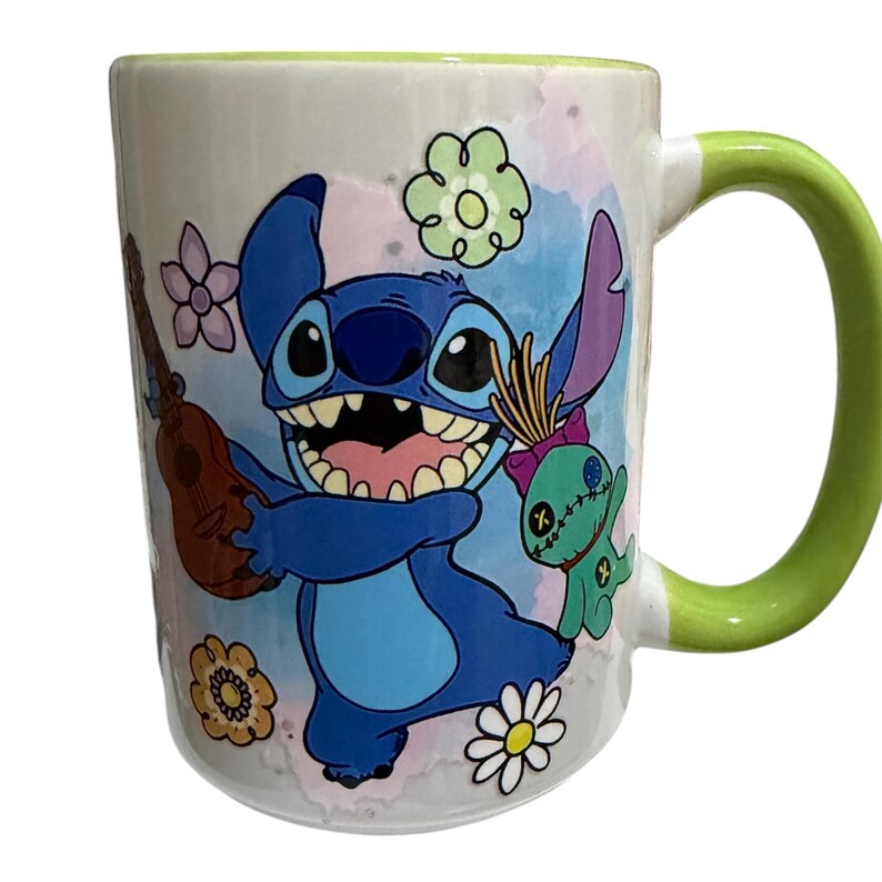 Pu&ograve; includere: Tazza in ceramica bianca con Stitch di Lilo & Stitch, che tiene un ukulele e sorride. La tazza ha un manico e un bordo verdi, con uno sfondo floreale e acquerello colorato. Un design divertente e stravagante.
