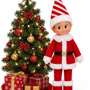 May include: A doll dressed in a red and white Santa suit with a matching striped hat stands beside a small, lit Christmas tree decorated with red and gold ornaments, a gold star topper, and three wrapped gift boxes at the base.