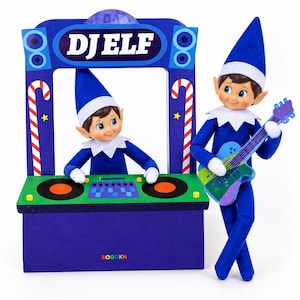 May include: Two blue-clad elf dolls with pointed hats and white collars. One elf stands behind a cardboard DJ booth labeled DJ ELF with two turntables and a mixer. The other elf stands to the side holding a blue and green toy electric guitar.