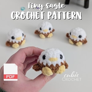 May include: A hand holding a white, brown, and yellow crocheted eagle. The image includes three other similar eagles and the text "Tiny eagle CROCHET PATTERN". A PDF icon is in the lower left corner.
