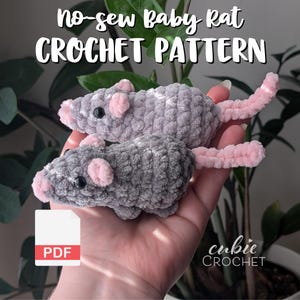 Puede incluir: Un patrón de crochet para una rata bebé sin costuras. El patrón está disponible para descargar en PDF. En la imagen se muestran dos ratas bebé de crochet grises con colas rosas. Las ratas están sostenidas en la mano de una persona.