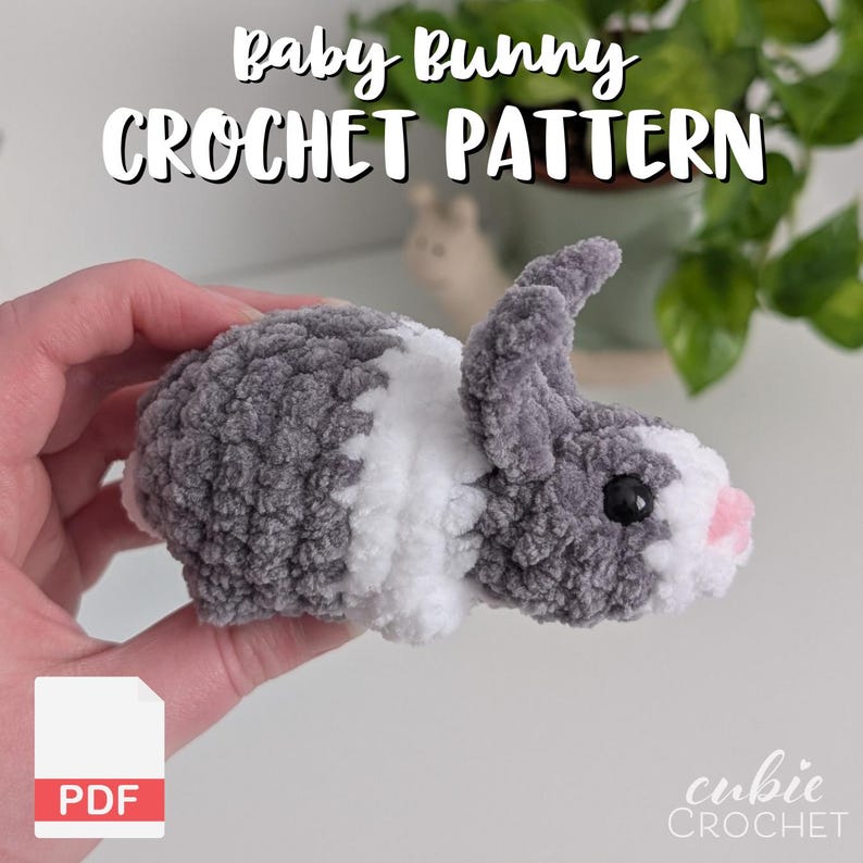 Op de afbeelding: Een gehaakt babykonijn in grijs, wit en roze. Het konijn heeft een zachte textuur en zwarte ogen. De afbeelding bevat de tekst "Baby Bunny Crochet Pattern" en een PDF-pictogram.