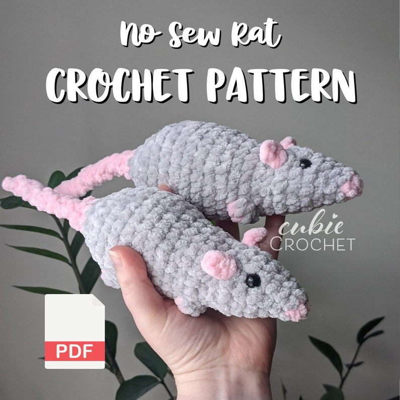 A hand holding up two gray crocheted rat plushies with light pink noses, ears, and tails. Text at the top of the image reads "No-Sew Rat Crochet Pattern". There is a PDF icon at the bottom left of the image.