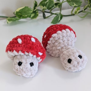 May include: Two crocheted mushroom toys with red and white caps and white bodies with black eyes.