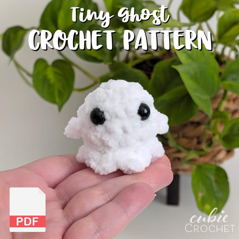 K&ouml;nnte beinhalten: Ein kleiner wei&szlig;er H&auml;kelgeist mit zwei schwarzen Kunststoffaugen. Der Text Tiny ghost CROCHET PATTERN steht oben und ein wei&szlig;es PDF-Symbol befindet sich in der unteren linken Ecke. Das Objekt besteht aus weichem, flauschigem wei&szlig;em Garn.
