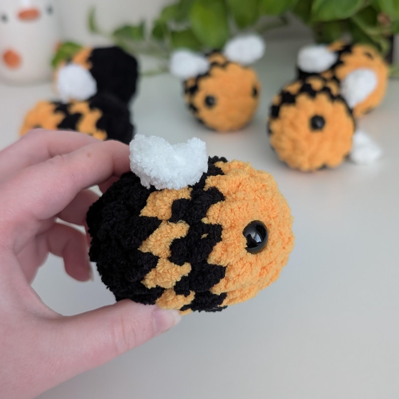 May include: Handmade plush bees in black, yellow, and white. The bees have black eyes and white wings. The plush toys are soft and fuzzy, perfect for children or as decorative items. The image shows several bees.