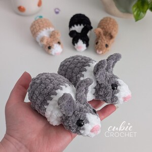 Op de afbeelding: Handgemaakte gehaakte cavia's en konijnen in verschillende kleuren, waaronder grijs, bruin en zwart. De pluche dieren hebben roze neuzen en zwarte ogen. De afbeelding bevat ook de tekst "cubie CROCHET".